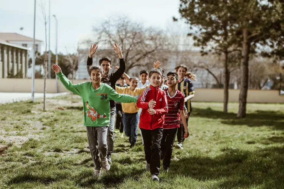 Children running on the grass in a park.